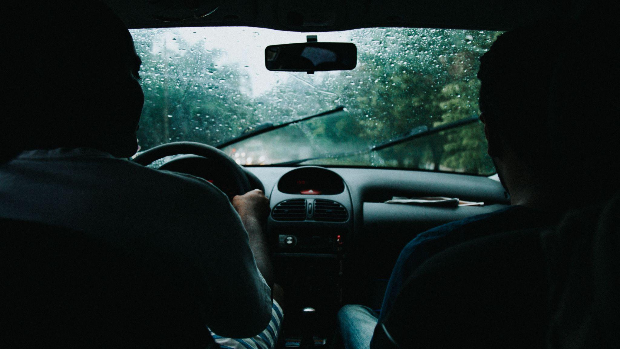 deux hommes en voiture roulant sous la pluie