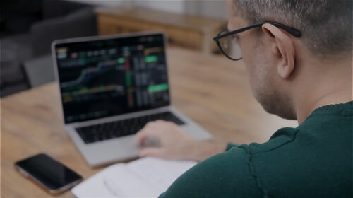 un homme faisant du trading financier sur son ordinateur