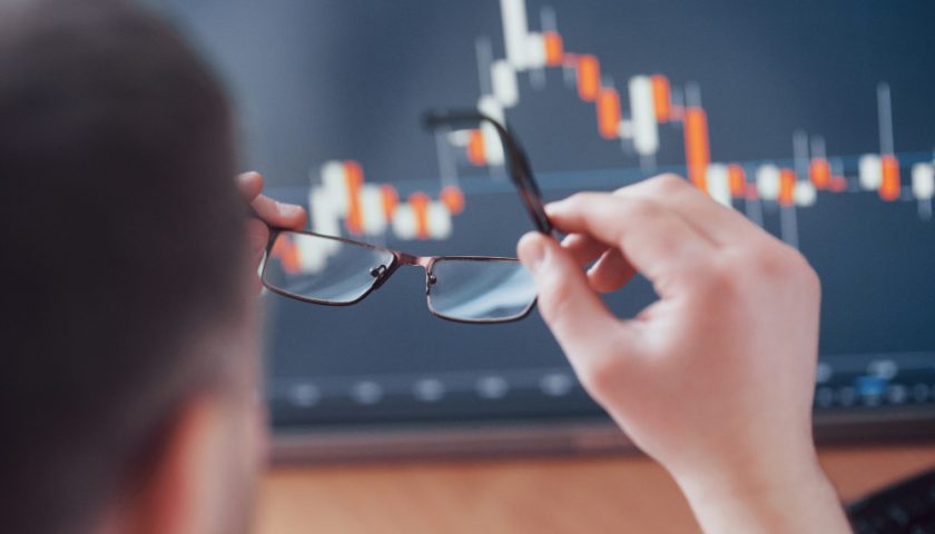 un homme qui tient une paire de lunette devant un ordinateur