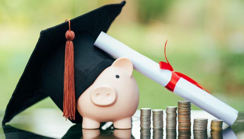 une tirelire cochon, un chapeau de diplômé, des pièces de monnaie et un document roulé