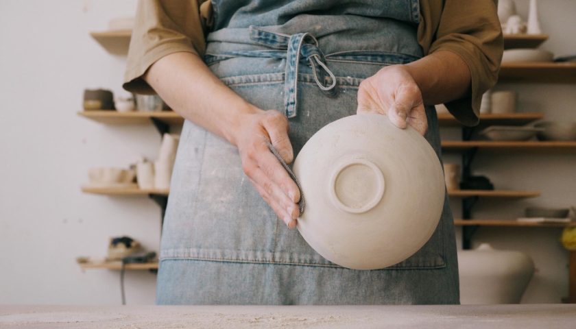 une femme montrant un bol fait maison en céramique